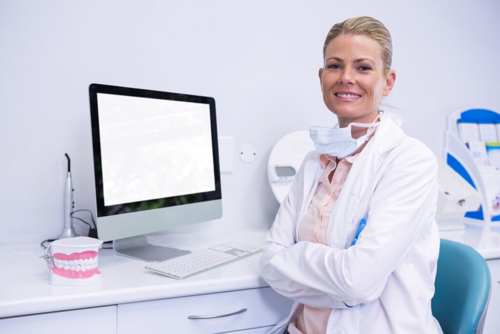 白衣を着た医者がパソコンの前に座り微笑んでいる