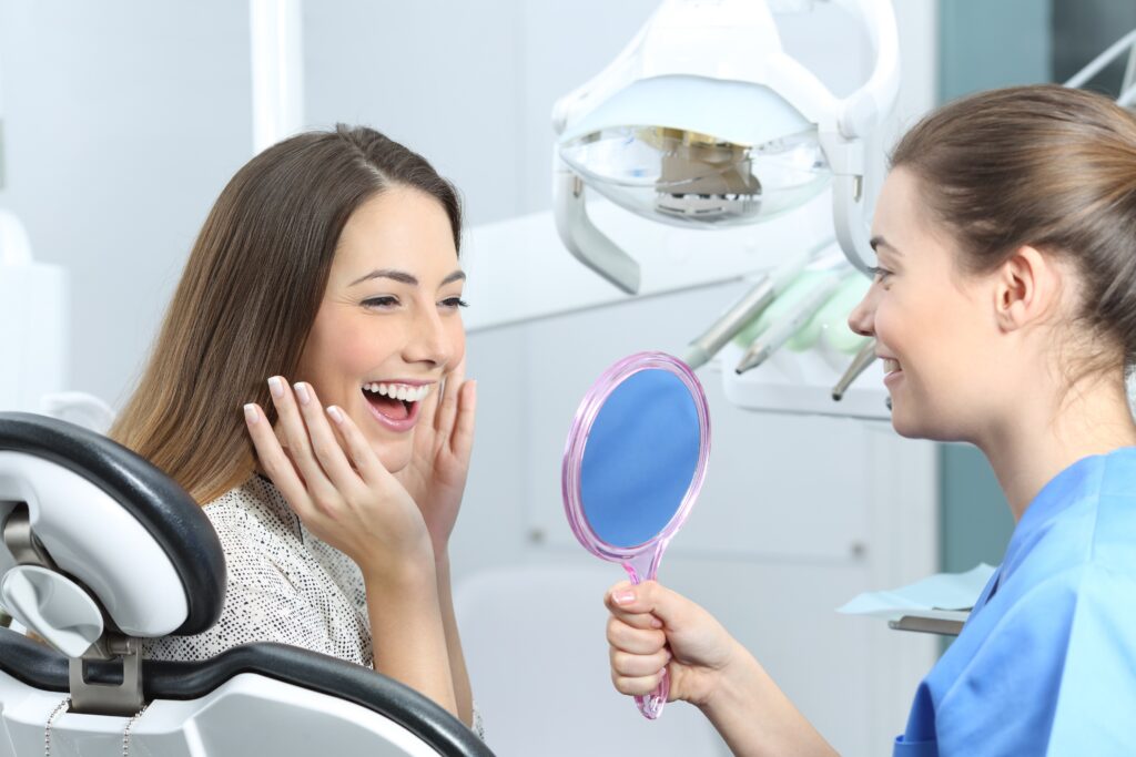 歯科医が女性患者に鏡で口元を見せている