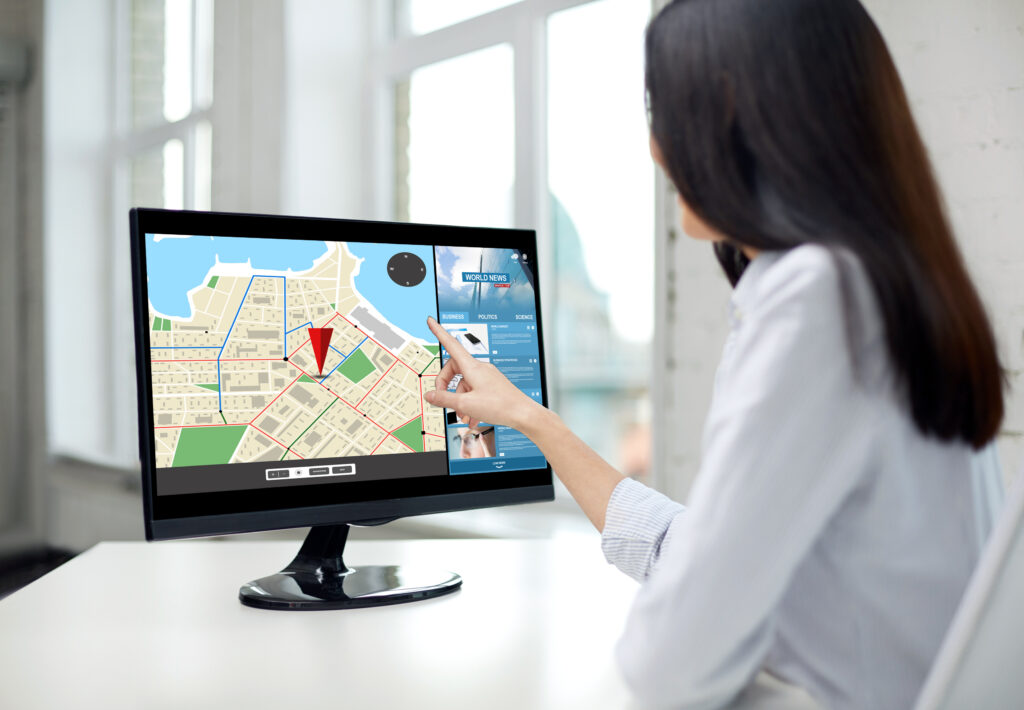 デスクトップパソコンに表示された地図を女性が見ている
