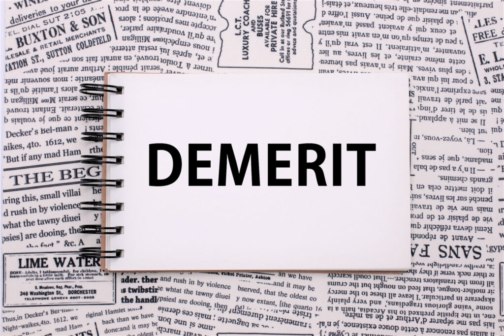 demeritと書かれたメモが英字新聞の上に置かれている